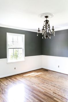 an empty room with hard wood floors and a chandelier