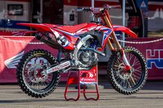 a red dirt bike parked on top of a stand