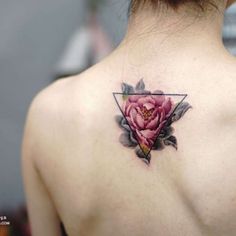 a woman's back with a pink flower tattoo on her left shoulder and behind the neck