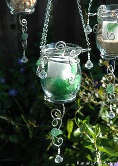 three glass vases with green and white decorations hanging from chains