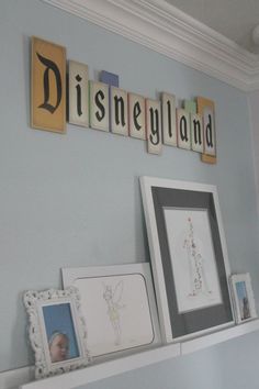 the wall is decorated with disney land letters and pictures on it, along with framed artwork