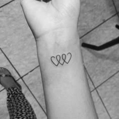 a small tattoo on the wrist of a woman with three hearts in it's center