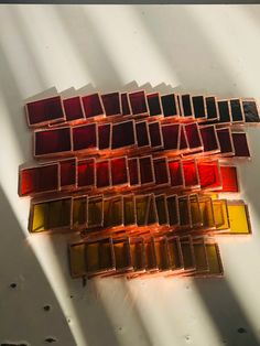 several different shades of colored glass sitting on top of a white surface with shadows coming from them