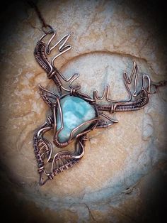 a necklace made with copper wire and turquoise stone in the shape of a deer's head