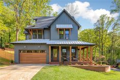 a large gray house with lots of windows on the front and side of it, surrounded by trees