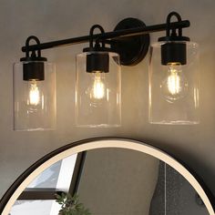 three light bathroom fixture with clear glass jars on the front and back of the lights