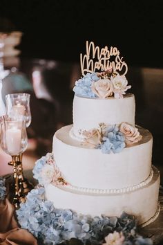 a three tiered cake with blue flowers on the table