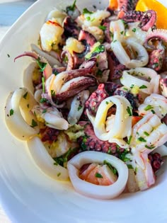 an octopus salad is served on a white plate