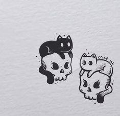 two stickers depicting cats and skulls on a white surface with black ink in the middle