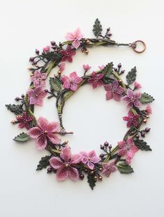 a close up of a wreath made out of flowers and leaves on a white surface