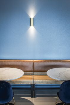 two tables and chairs in front of a blue wall with a light fixture on it