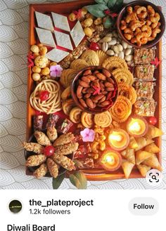 the platter is full of different types of snacks and nuts, with candles on it