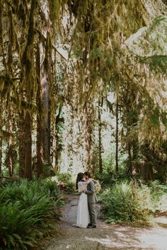 a bride and groom embracing in the woods