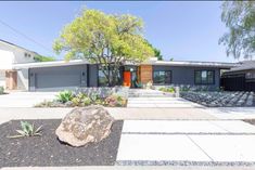 a modern house with large rocks in the front yard