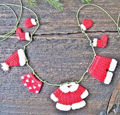 a red and white knitted christmas garland with santa hats, mittens and gloves