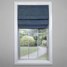 a window with a blue roman blind in front of it and trees outside the window