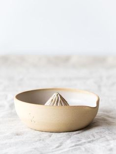 a white bowl sitting on top of a bed next to a wooden spoon and fork