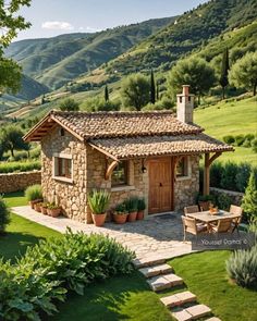 a small stone house in the middle of a lush green field with steps leading up to it