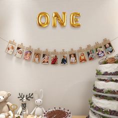 a table topped with lots of cake covered in photos and gold balloons that spell out the word one