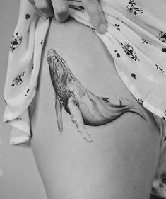 a woman's thigh with a whale tattoo on it