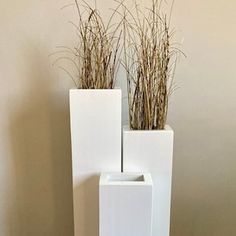 two tall white vases sitting next to each other on top of a wooden floor