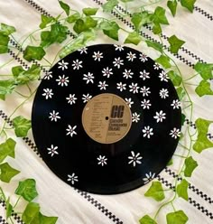 an old record sitting on top of a table covered in green leaves and white flowers