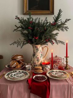 a table topped with plates covered in food next to a vase filled with pine branches