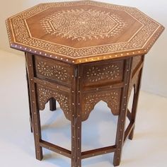 a wooden table with an intricate design on it's top and bottom, sitting against a white background