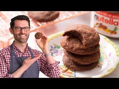 a man standing in front of a stack of cookies on a plate next to a jar of nutella