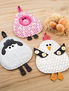 three farm animals are sitting on the floor next to an egg and some chicken eggs