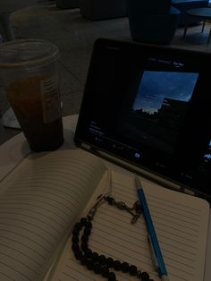 a laptop computer sitting on top of a table next to a pen and notebook with a chain around it