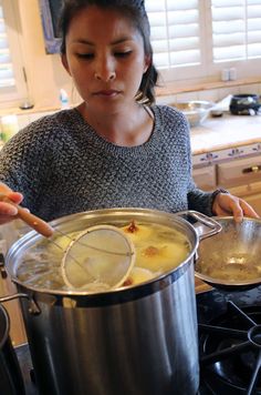 a woman is cooking food in a pot on the stove