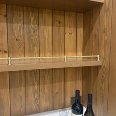 two bottles of wine sitting on top of a counter next to each other in front of wooden shelves