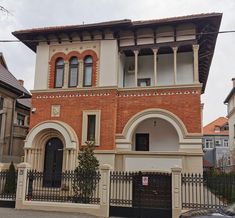 an old brick house with arched windows and iron fenced in gates on a street corner