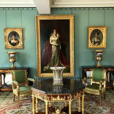 an ornately decorated room with blue walls and paintings on the wall, along with antique furniture