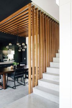 a dining room and kitchen area with wood slats on the wall, stairs leading up to an open floor plan