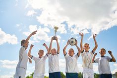 a group of young men holding up a soccer ball in the air with their hands