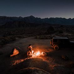 two people sitting around a campfire in the desert