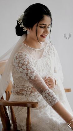 a woman sitting in a chair wearing a wedding dress and holding her hands on her knees