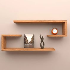 two wooden shelves with books, an alarm clock and a statue on one shelf next to each other