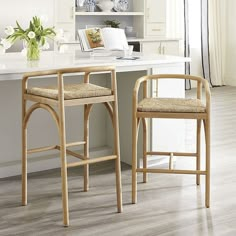 two wooden stools sitting in front of a white counter top next to a window