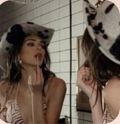 a woman wearing a cow hat in front of a mirror with her tongue sticking out