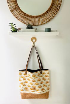 a handbag hanging on the wall next to a mirror and shelf with a potted plant