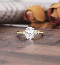 a close up of a ring on a wooden surface with roses in the back ground