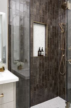 a walk in shower sitting next to a white sink and counter top under a mirror