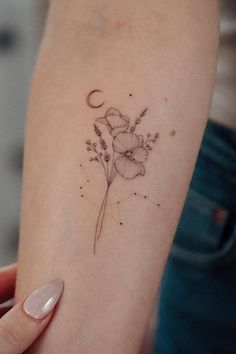 a woman's arm with a flower and the moon tattoo on her left arm