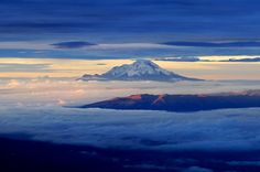 a view of the top of a mountain with clouds below