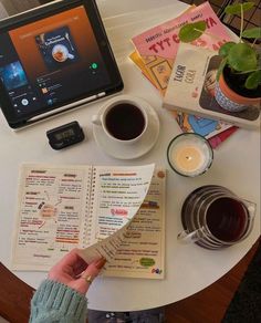 a person holding a knife over a menu next to a cup of coffee and a laptop