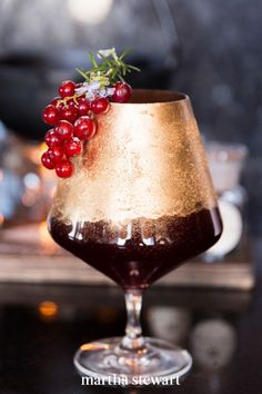 a glass filled with liquid and some red berries on top of it, sitting on a table