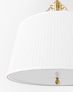 a white lamp hanging from the ceiling with a gold fitting on it's side